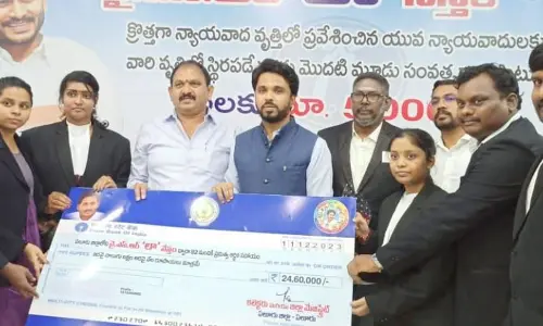 Collector Prasanna Venkatesh handing over cheque to beneficiaries of YSR Law Nestham in Eluru on Monday