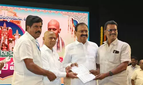 TTD Trust Board Chairman Bhumana Karunakara Reddy and EO AV Dharma Reddy distributing house site documents to an employee at Mahati auditorium in Tirupati on Thursday