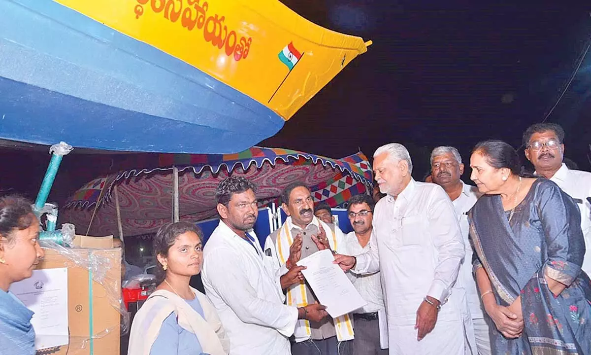 Union Minister Parshottam Rupala distributing boat and tools to a beneficiary at Pallepalem of Kothapatnam mandal on Monday night