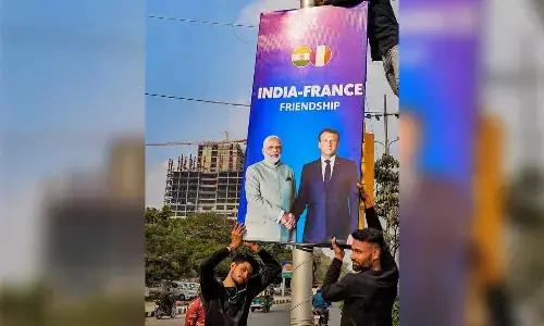 A worker fixes a hoarding with a pole ahead of the France President Emmanuel Macron and Prime Minister Narendra Modi’s visit to the Amber Fort, Jantar Mantar and Hawa Mahal, in Jaipur on Wednesday