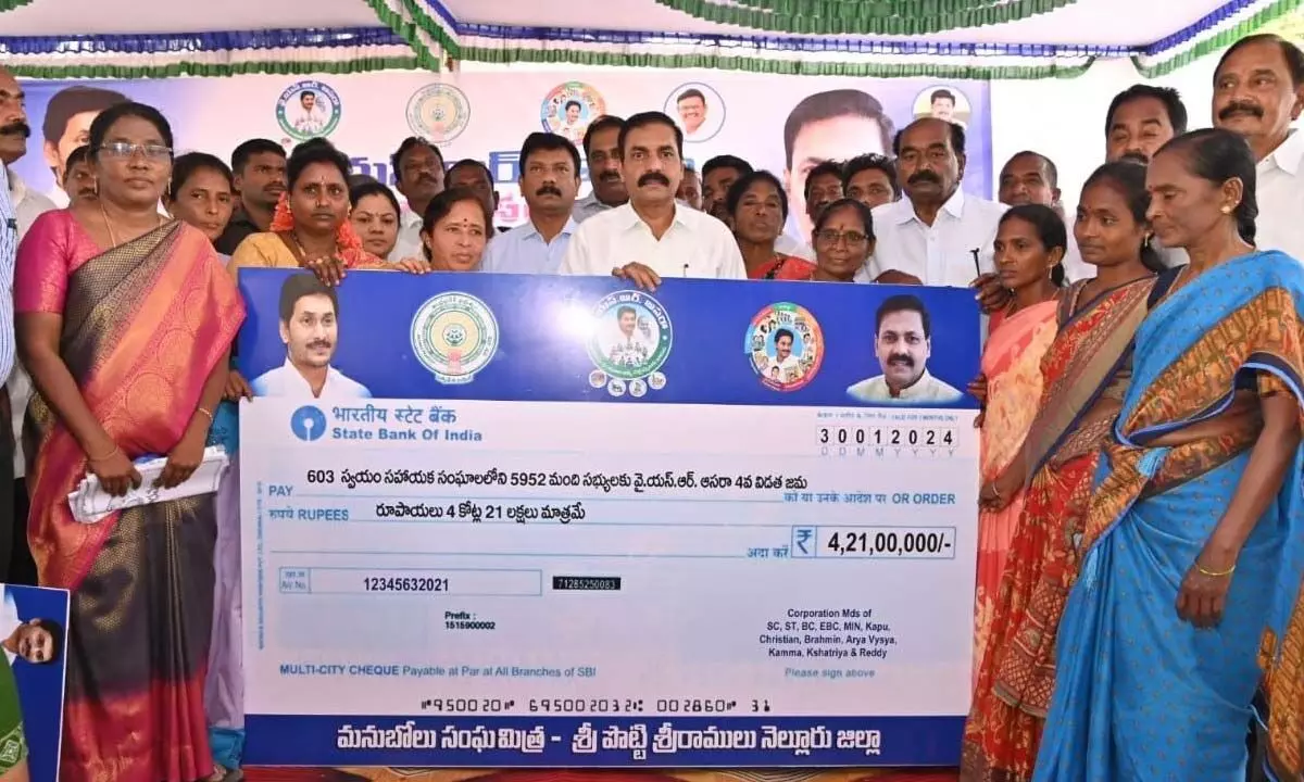 Agriculture Minister Kakani Govardhan Reddy handing over a cheque towards financial assistance under YSR Aasara scheme to the beneficiaries in Manubolu mandal in Nellore district on Tuesday