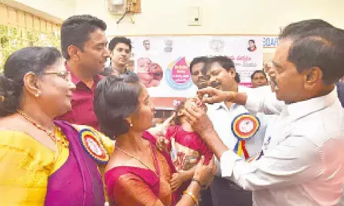 Deputy CM K Narayana Swamy administering polio drops to a child at Vedalla Cheruvu of ST Colony in Renigunta mandal on Sunday. District Collector G Lakshmisha and DM&HO Dr U Sreehari are also seen.