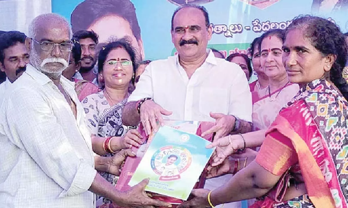 MLA Balineni Srinivasa Reddy presenting the beneficiaries with registered deeds for housing plots at Puli Venkatareddy Colony in Ongole on Monday