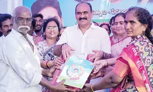 MLA Balineni Srinivasa Reddy presenting the beneficiaries with registered deeds for housing plots at Puli Venkatareddy Colony in Ongole on Monday