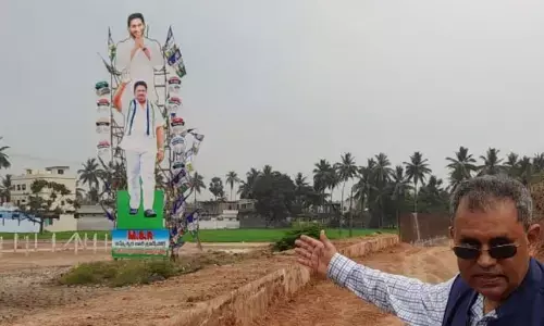 Dr Nimmagadda Ramesh Kumar, secretary of Citizens for Democracy pointing to a huge cutout of the ruling YSRCP at Jonnada bridge in Amebdkar Konaseema district on Tuesday