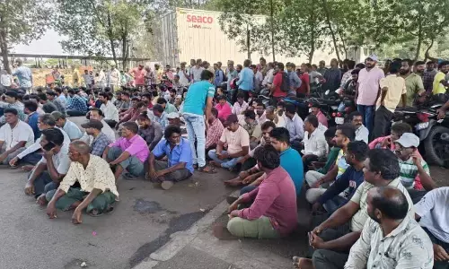 Workers staging a sit-in protest demanding hike in wages, among others, near the port in Visakhapatnam on Saturday.
