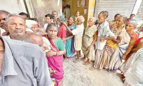 Pensioners stand in a queue line at a bank to withdraw pensions in Vizianagaram on Thursday