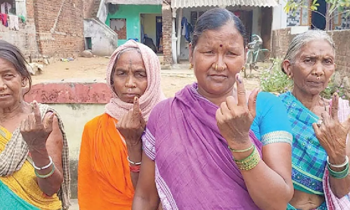 Tribal women show their inked fingers after casting votes