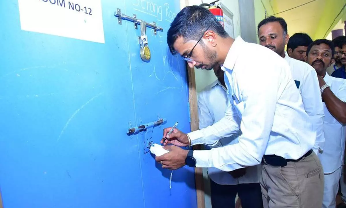 District Collector Dr Vinod Kumar signing on the sealed lock of the strongrooms where EVMs are kept in Anantapur on Tuesday