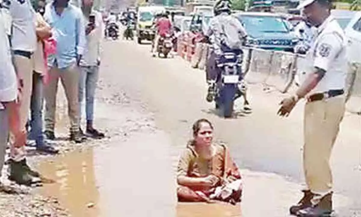 Woman sits on pothole to protest bad roads in Nagole