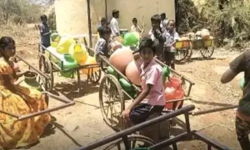 Residents of Haligera village waiting at an agriculture borewell to fetch drinking water