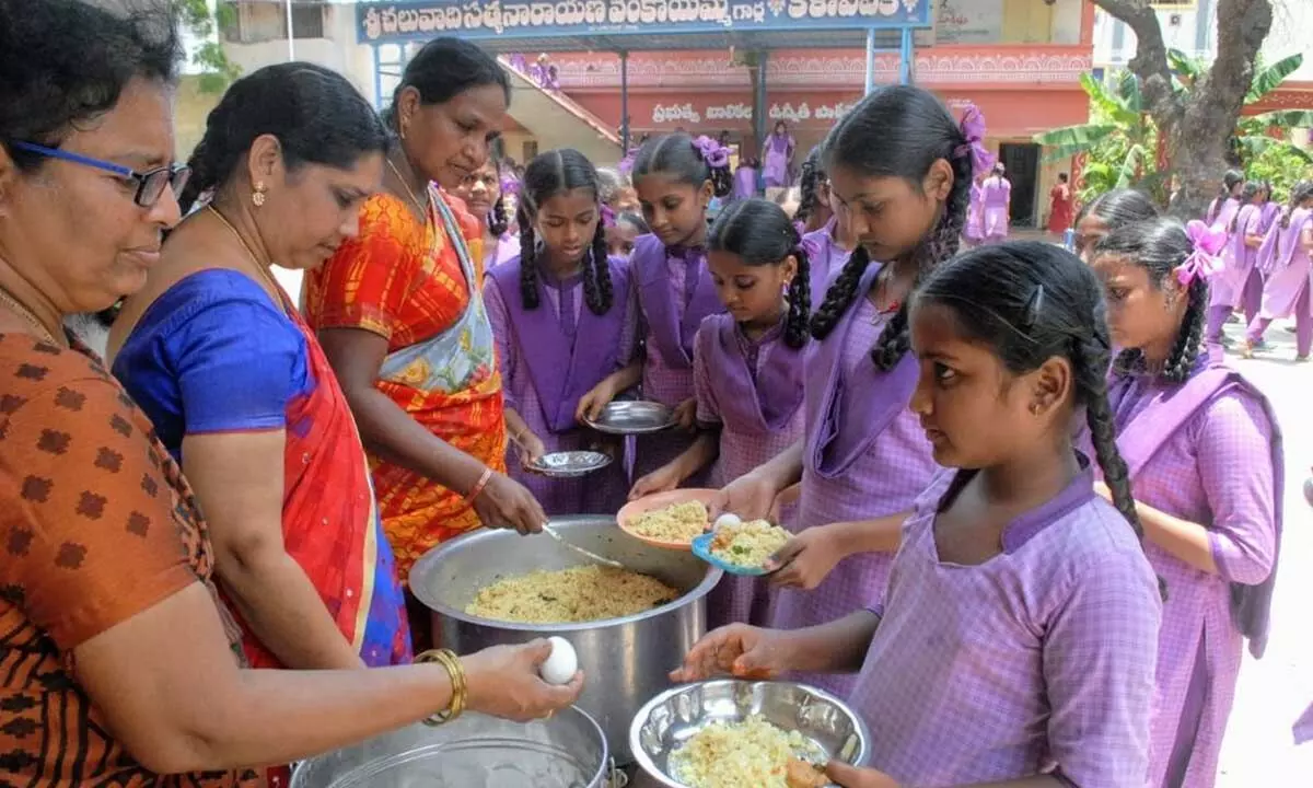 Students having midday meals at Govt Girls High School in Bandlamitta of Ongole on Tuesday