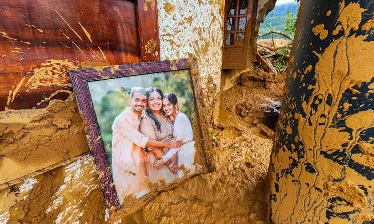 A framed photograph lies partially covered in mud at a damaged house after landslides hit hilly villages in Wayanad on Tuesday