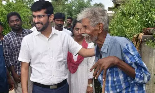District Collector O Anand giving away pension to an elderly man in Kudithipalem village on Thursday