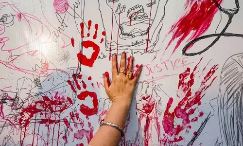An artist puts her handprints on a wall during a protest against the alleged sexual assault and murder of a postgraduate trainee doctor, at Academy of Fine Arts, in Kolkata on Monday