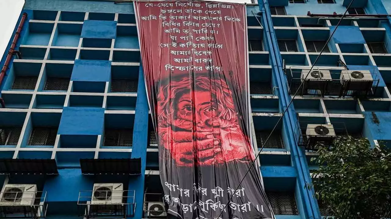 Junior doctors hang a giant poster from the roof of the R G Kar College and Hospital during their protest against alleged rape and murder of a woman trainee doctor of the hospital, in Kolkata on Tuesday