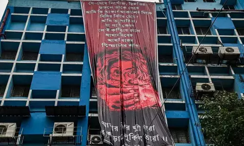 Junior doctors hang a giant poster from the roof of the R G Kar College and Hospital during their protest against alleged rape and murder of a woman trainee doctor of the hospital, in Kolkata on Tuesday