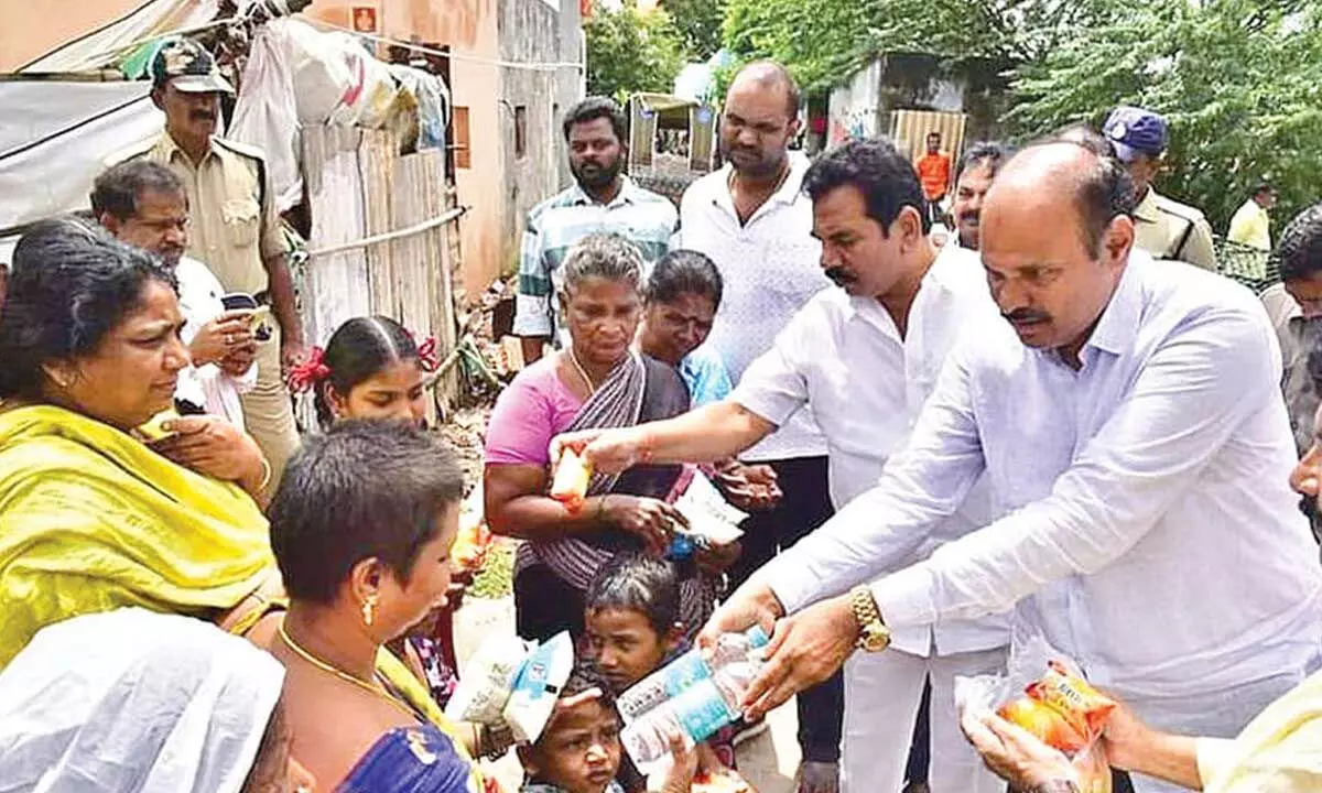 Minister Kolusu Parthasarathy distributes food, milk and water to flood victims in Krishna Lanka in Vijayawada on Friday