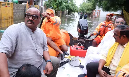 Agriculture Minister K Atchannaidu going on a boat to the  flood-affected areas in Vijayawada on Sunday
