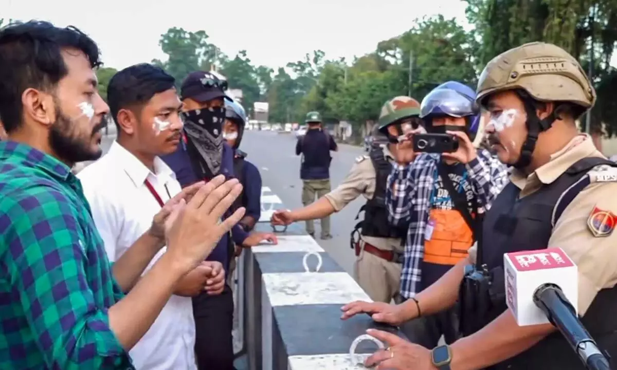 Security personnel talk to students during their protest over recent violence, in Imphal on Tuesday.