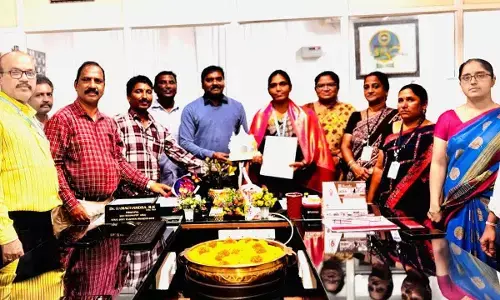 Principal of Government College (Autonomous) Dr Ramachandra RK along with faculty members and attendees congratulating Dr P Surekha on being conferred with the award