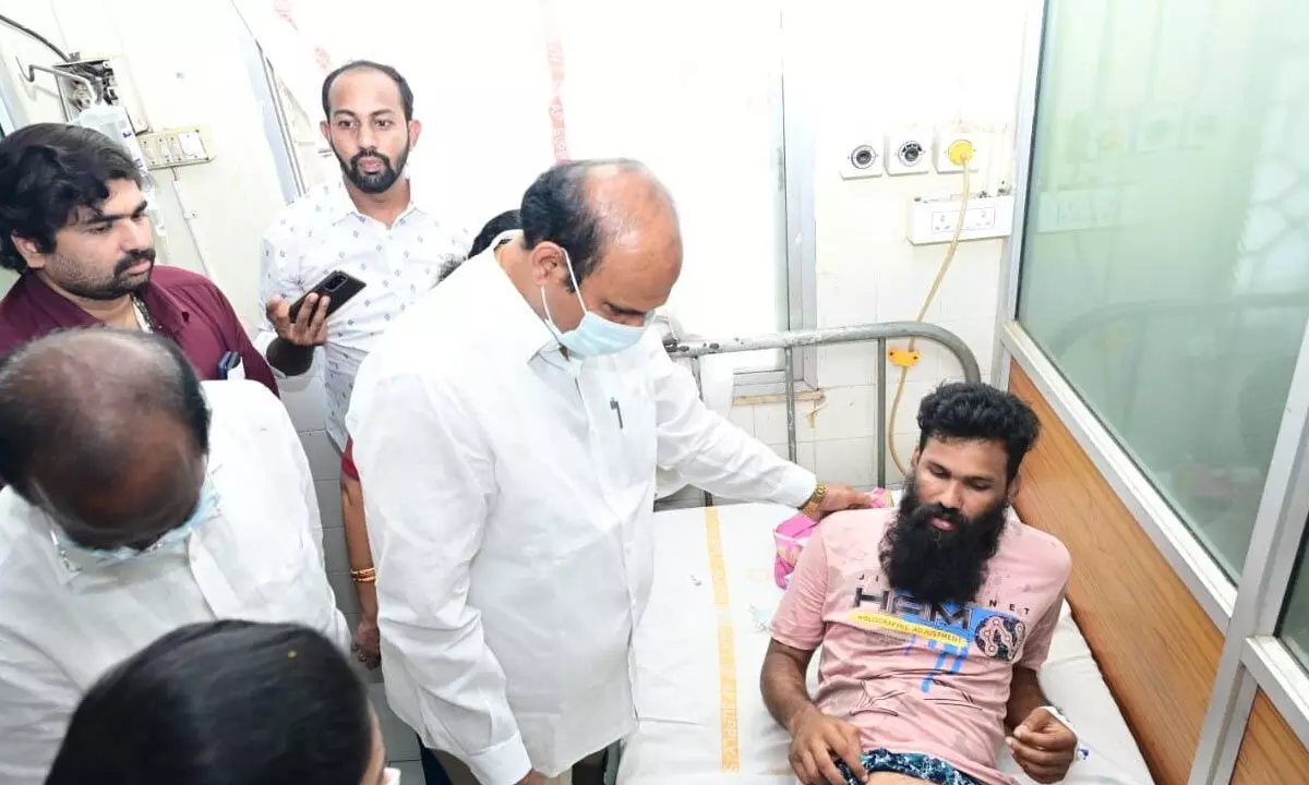 Minister Kolusu Parthasarathy consoling an injured person undergoing treatment at a hospital in Eluru