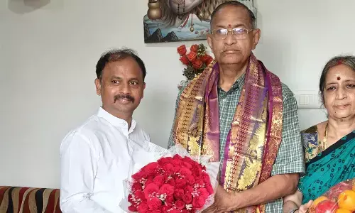 Samagra Shiksha SPD  B Srinivasa Rao presenting a bouquet to Chaganti Koteswara Rao and his spouse at their residence in Kakinada on Friday
