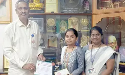 Dr M Ramesh, Principal of PB Siddhartha College of Arts and Science, congratulating Durga Bhavani for securing second place in essay writing in Vijayawada on Saturday