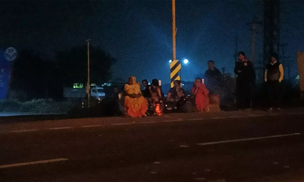 Bus passengers waiting for another vehicle, after the bus tyre was punctured near Kurnool