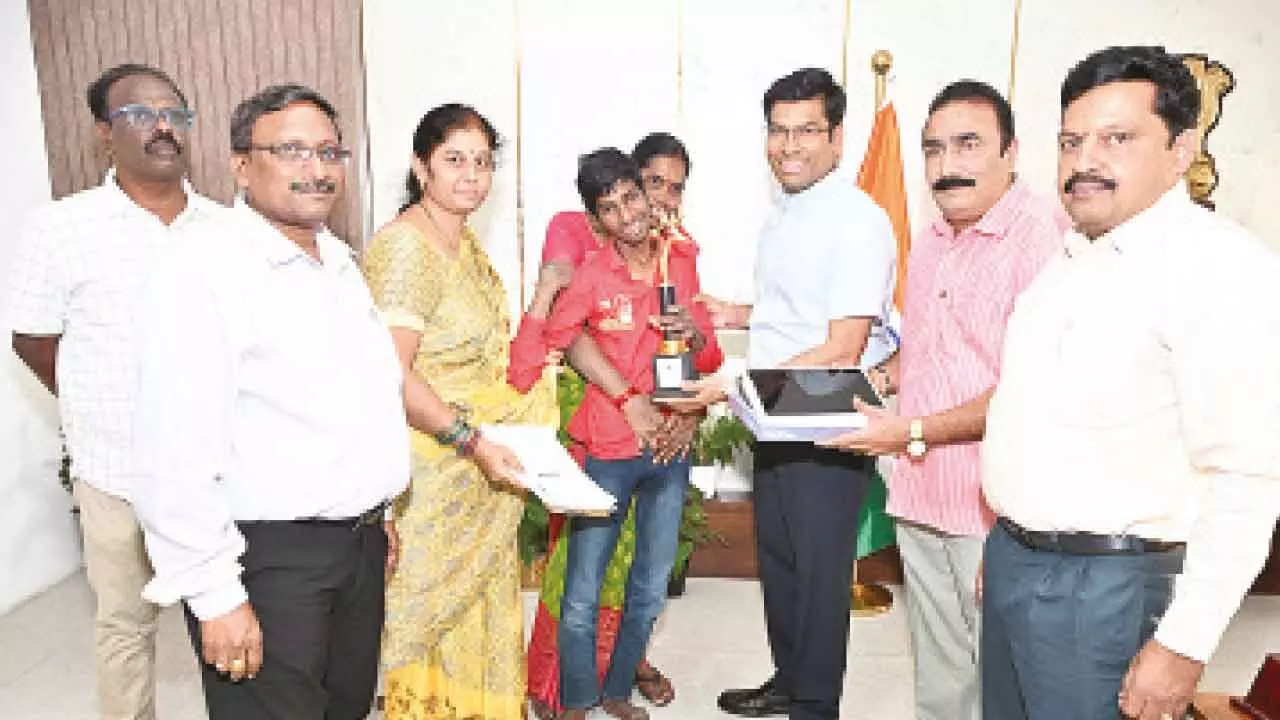 District Collector Dr S Venkateswar presenting a tab to V Ramesh in Tirupati on Tuesday. DEO KVN Kumar, Teacher Bhavani and others are also seen.