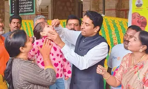 Collectors administer polio drops to children
