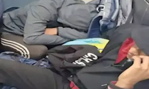 Students sit near toilets during return train journey