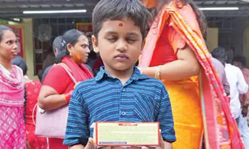 A child holding a box of laddu prasadam at the Kanaka Durga Temple during the Dasara Sarannavaratri festivities