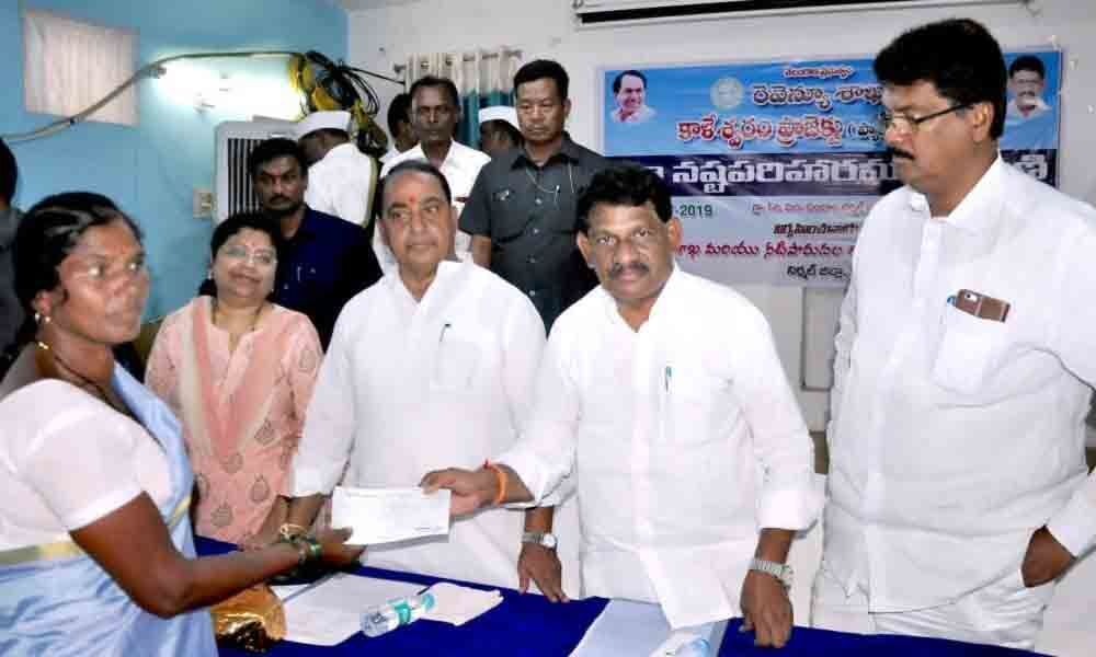 Minister A Indrakaran Reddy distributes compensation cheques to farmers in Nirmal