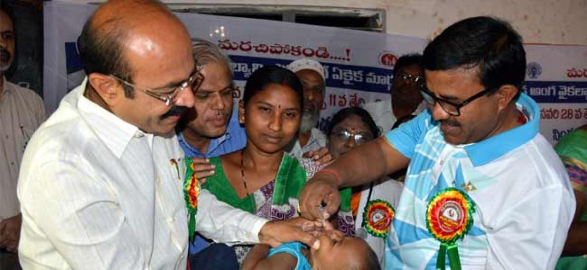 Collector administers polio drops to children